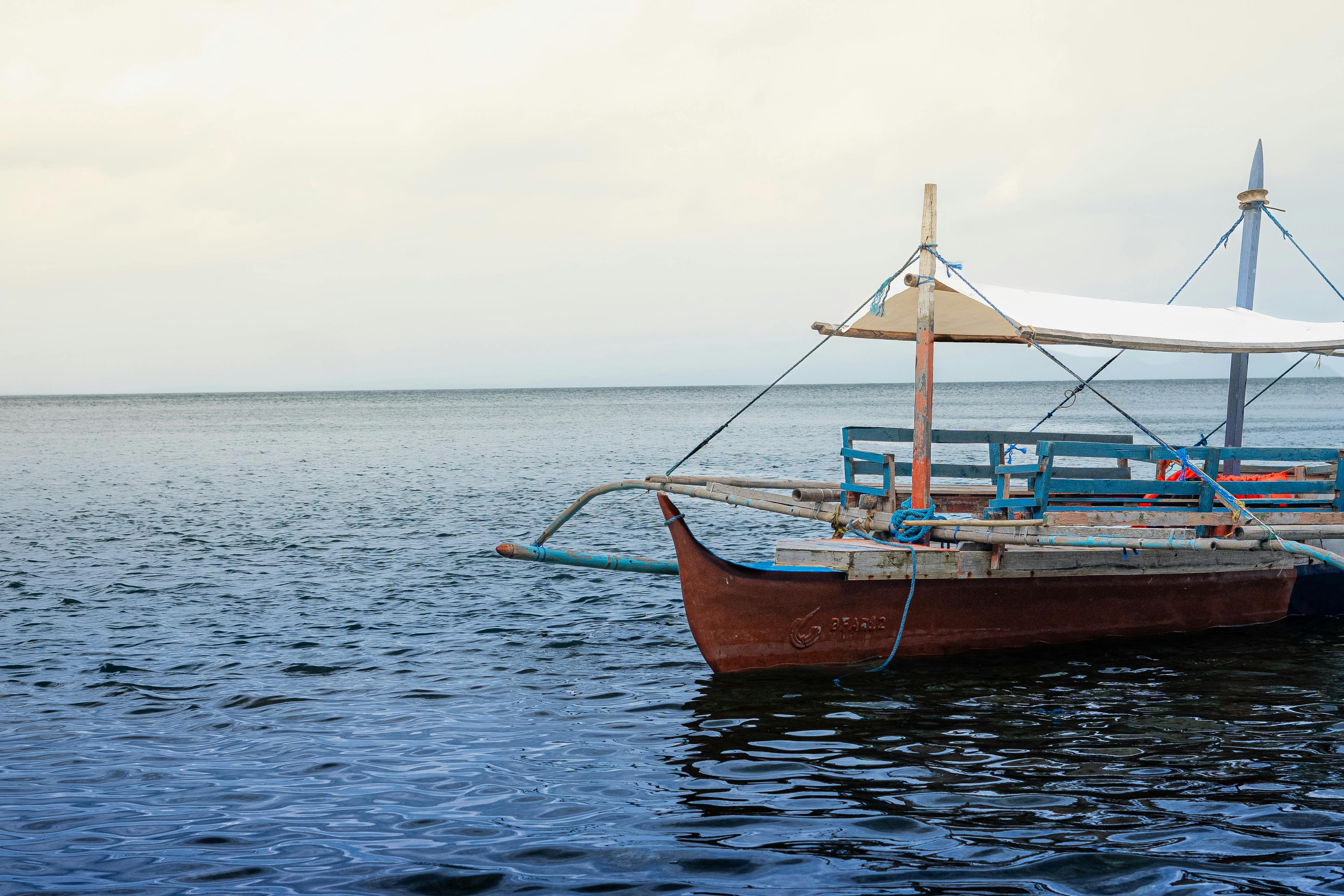 一艘带有白色天篷的经典木制船停靠在宁静的大海上，非常适合沿海冒险
