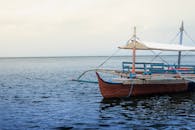 一艘带有白色天篷的经典木制船停靠在宁静的大海上，非常适合沿海冒险