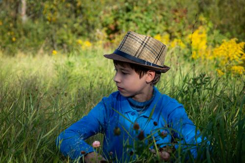 Free Young boy in a straw hat enjoying a sunny day in a lush meadow. Stock Photo