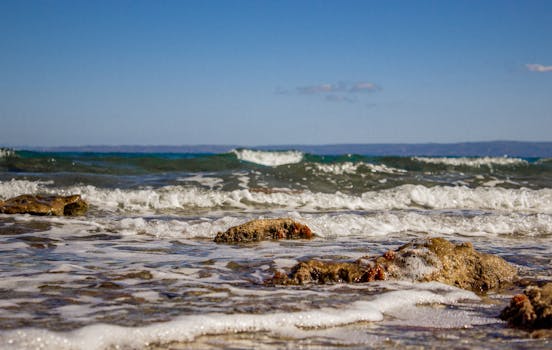 在蔚蓝的天空下，海浪轻轻拍打着希腊哈尼奥蒂的岩石海岸