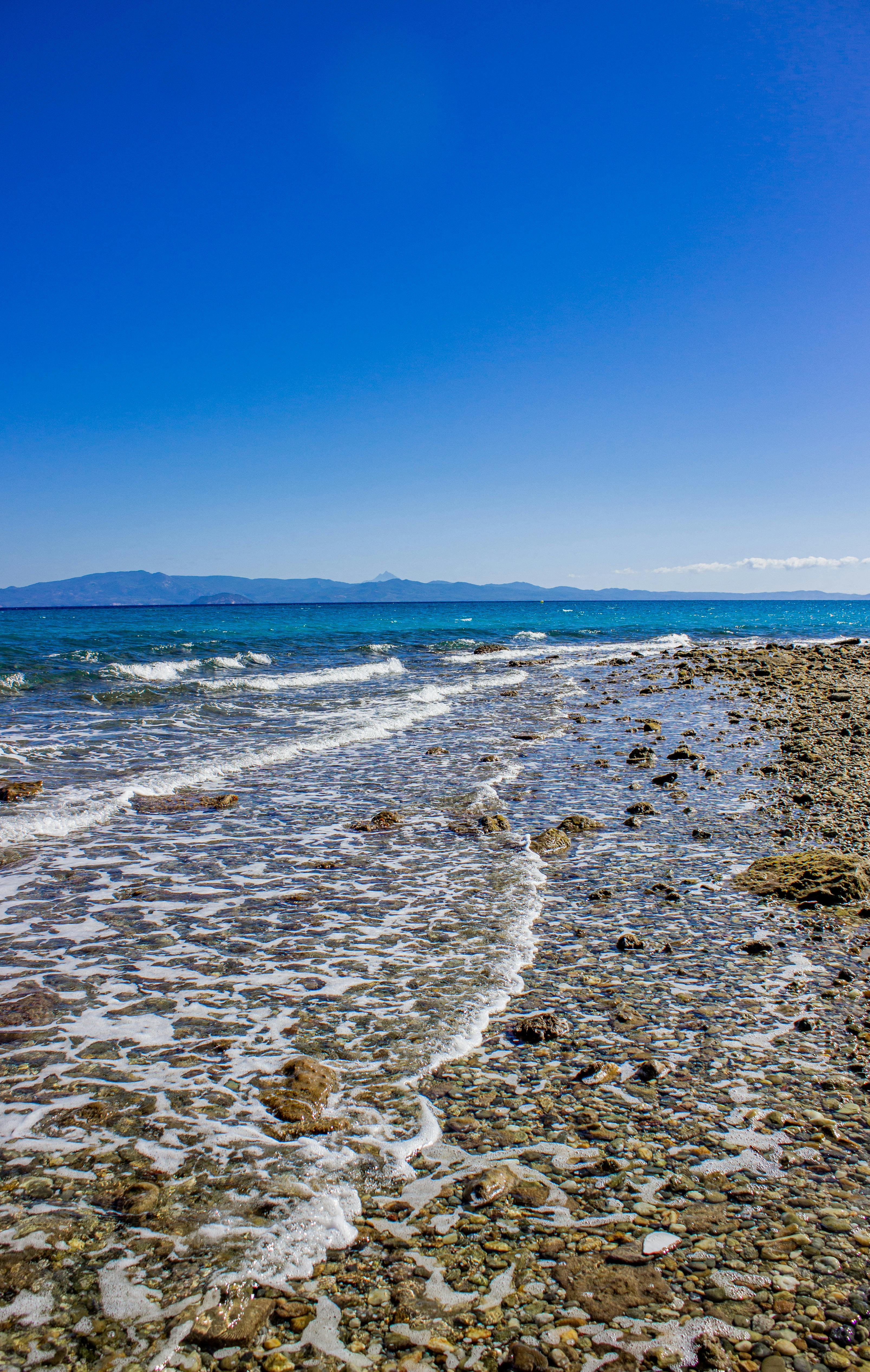 在希腊哈尼奥蒂的一个岩石海滩，进行和平拍摄时，晴朗的蓝天为画面增添了宁静与和谐的氛围