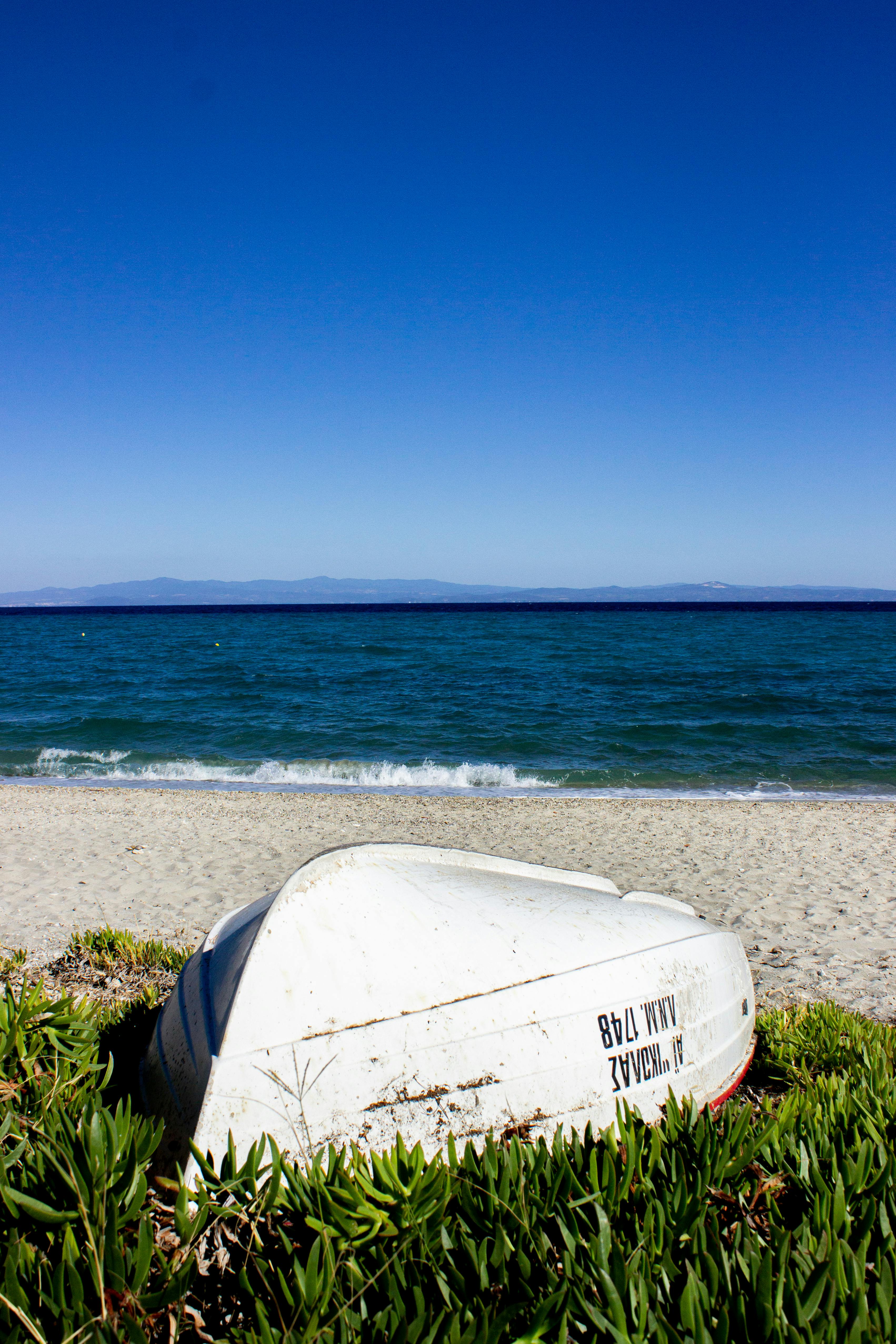白色的船倒在希腊哈尼奥蒂的沙滩上，蔚蓝的天空下