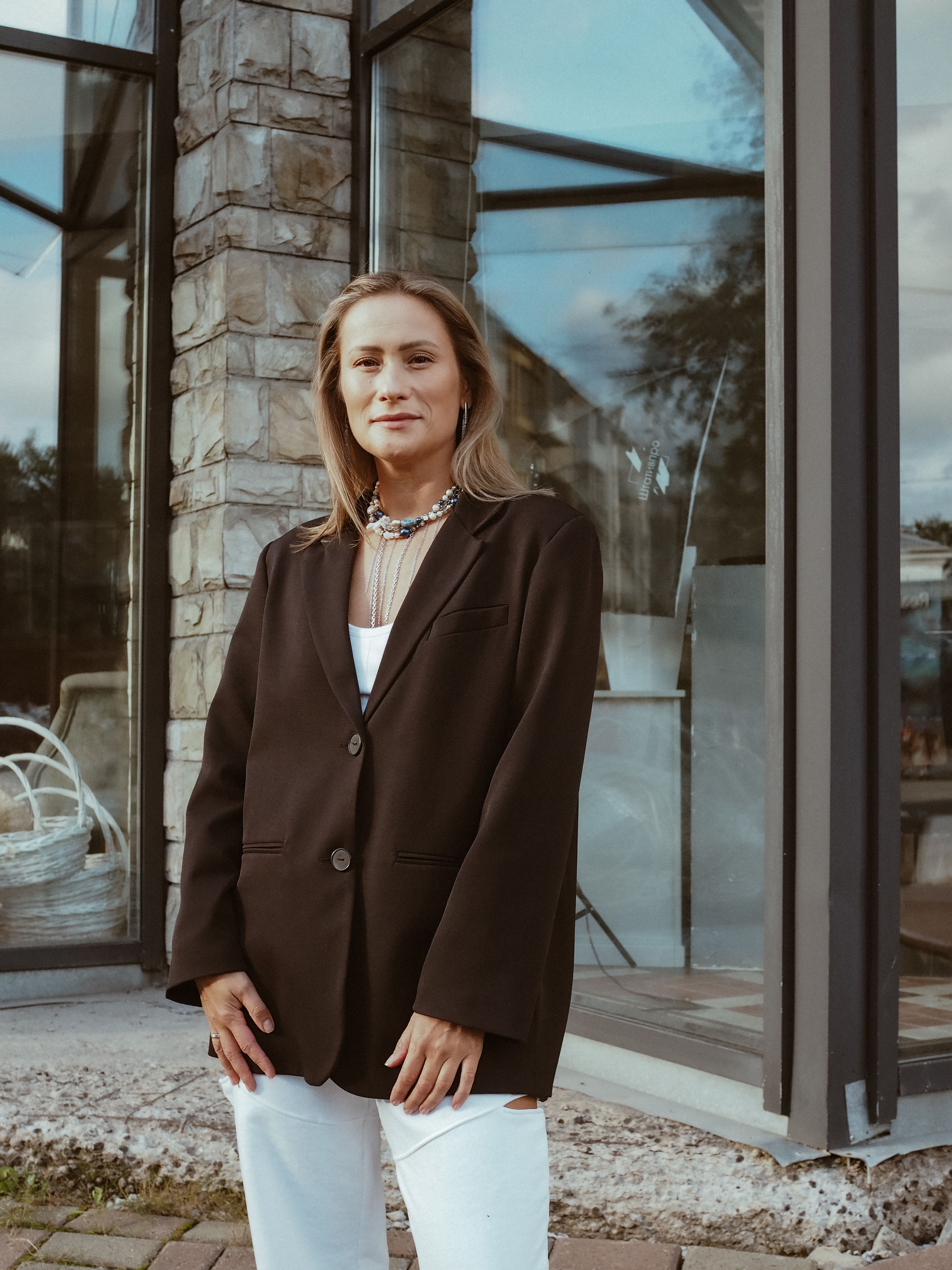 Free Portrait of a confident woman wearing a blazer standing outside a building. Stock Photo