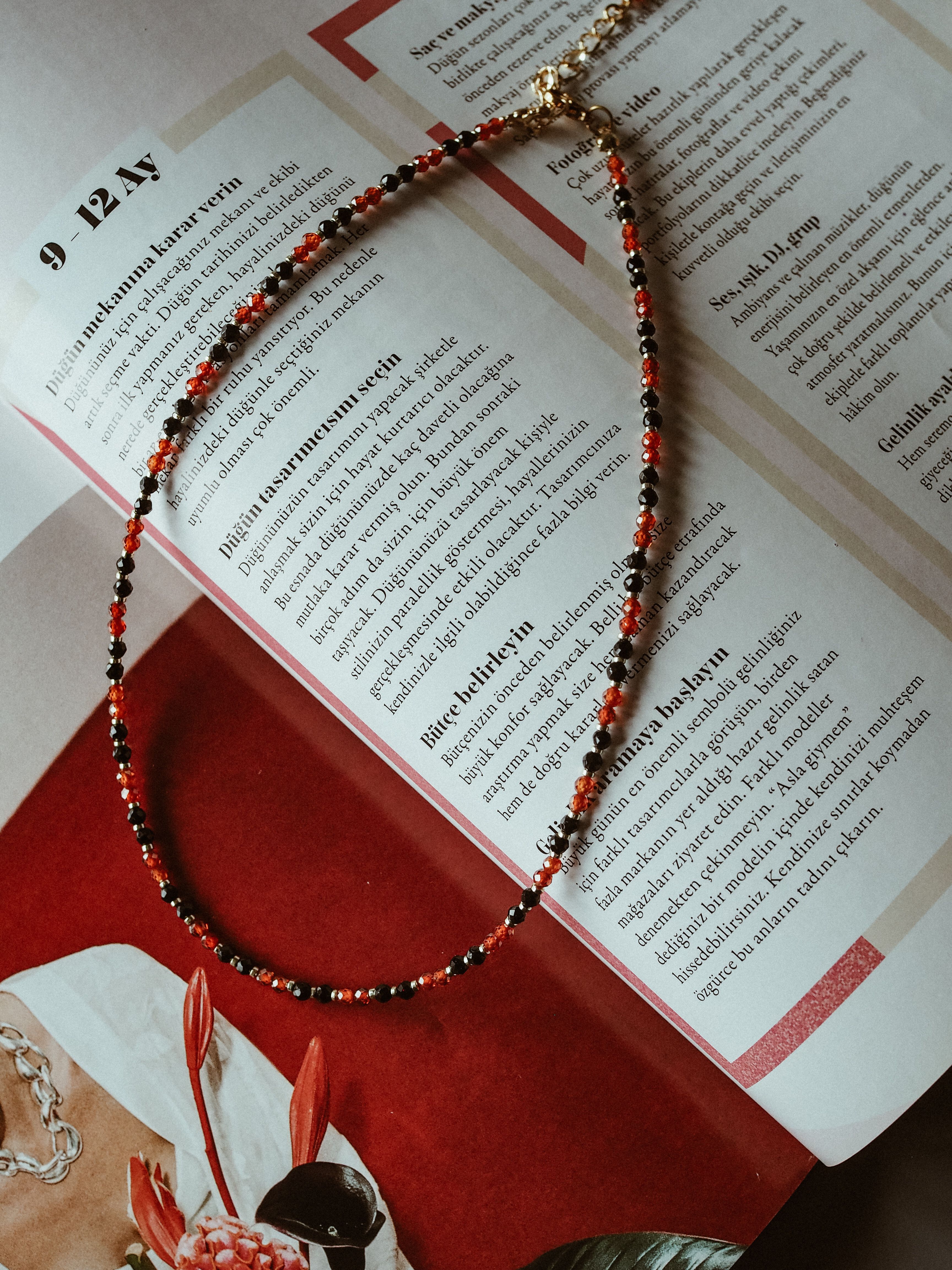 Free Colorful beaded necklace displayed on open magazine, perfect for fashion flat lay photography. Stock Photo