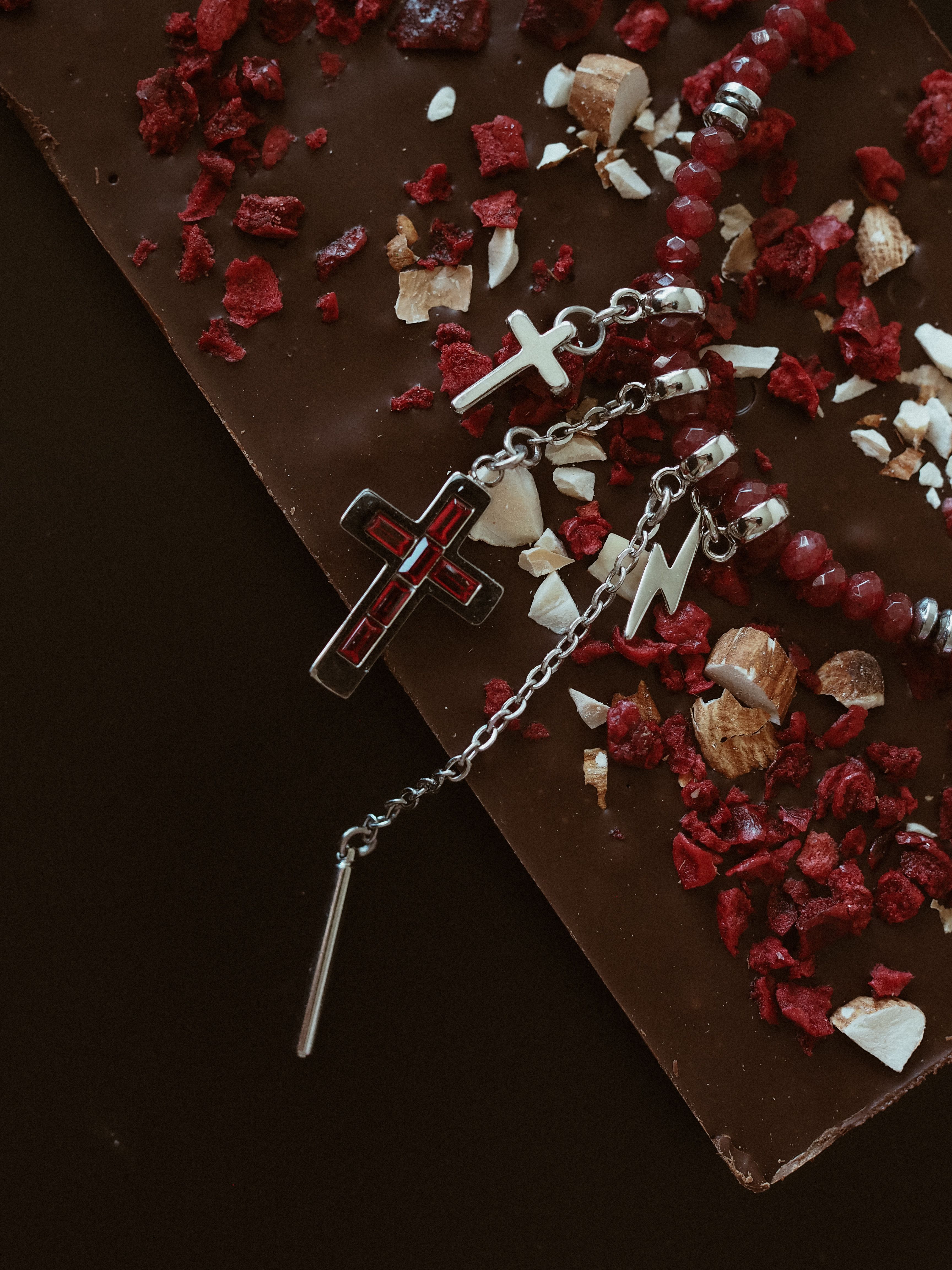 Free Red bead necklace with cross on rich chocolate. Ideal for dessert themes. Stock Photo