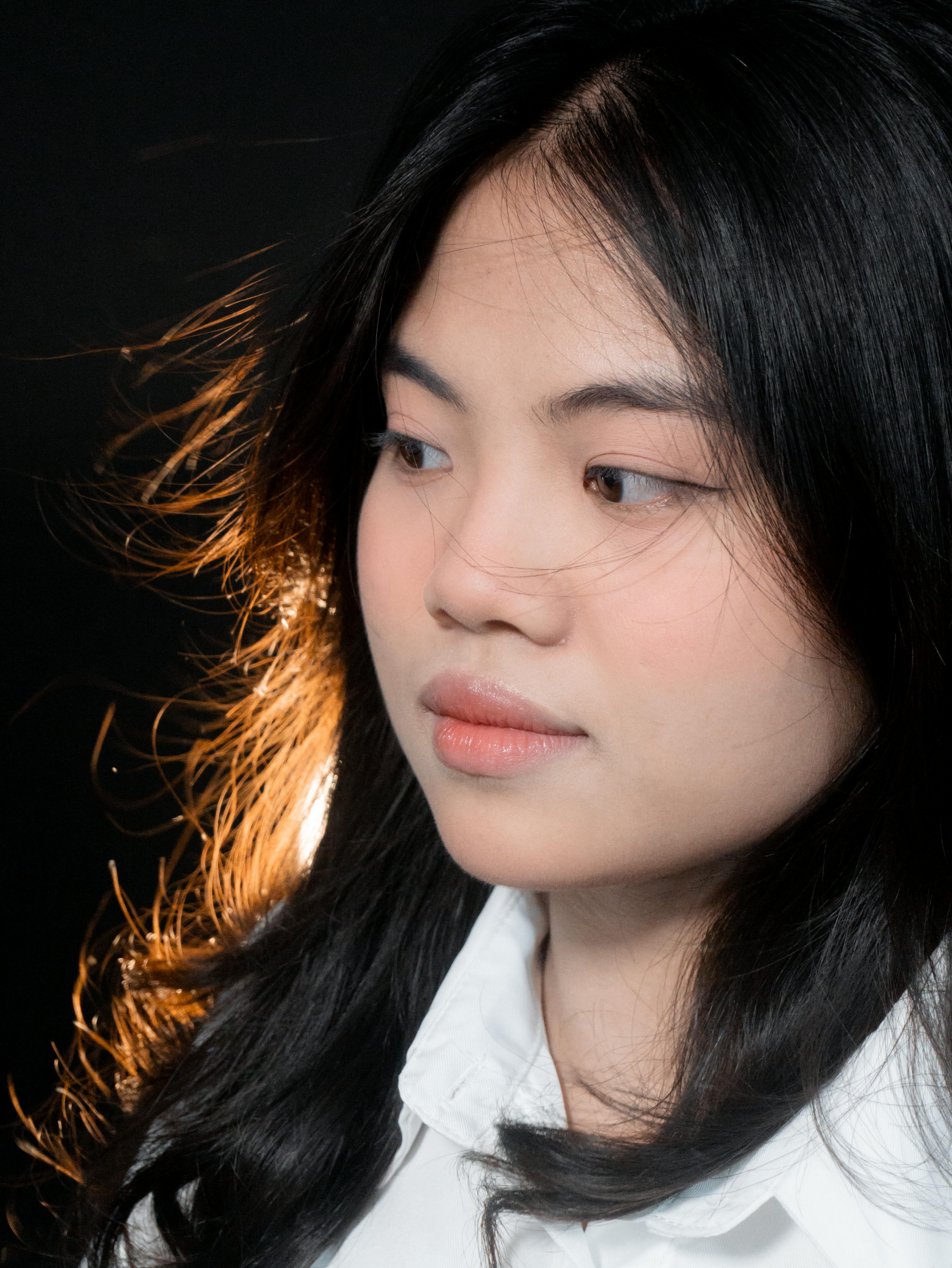 一位留着黑色长发、穿着白色衬衫的女性的工作室肖像