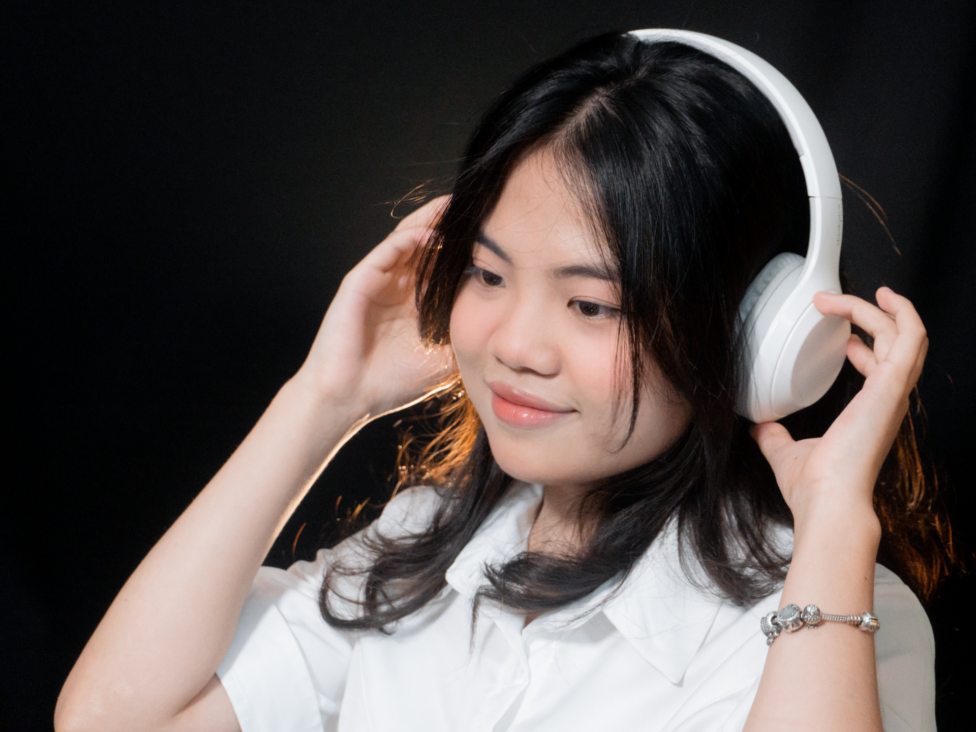 Asian woman with headphones enjoying music, showcasing happiness and relaxation.