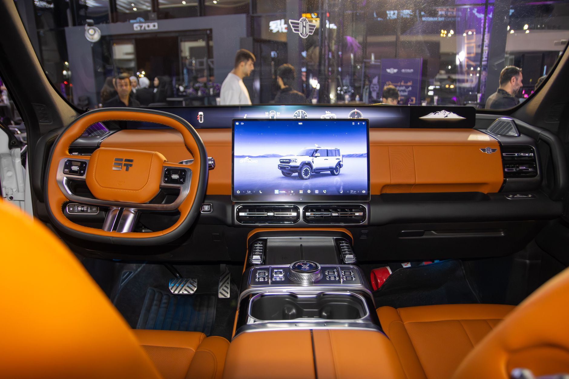 A modern, sleek electric vehicle dashboard with orange leather and touchscreen controls.