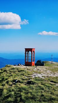Vibrant landscape view from the mountains of Sinaia, Romania featuring a unique red phone booth.