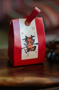 Red Chinese gift box with elegant calligraphy on wooden table, suitable for festive themes.