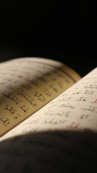 Detailed close-up of a book open to a page with Arabic script, captured with dramatic lighting.