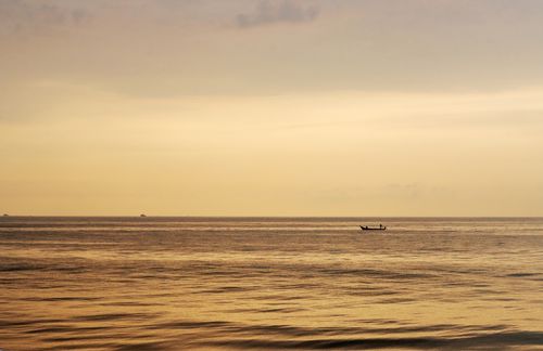 Free Tranquil ocean view at sunset featuring a lone boat on the horizon, perfect for peaceful themes. Stock Photo
