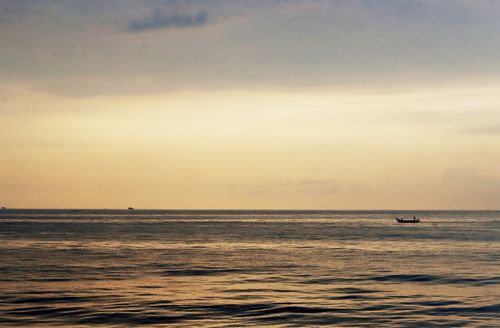 Free Serene seascape at sunrise with a lone boat, captured in Puducherry, India. Stock Photo