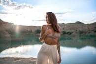 日落时分，年轻女子身穿夏装，站在宁静的湖边