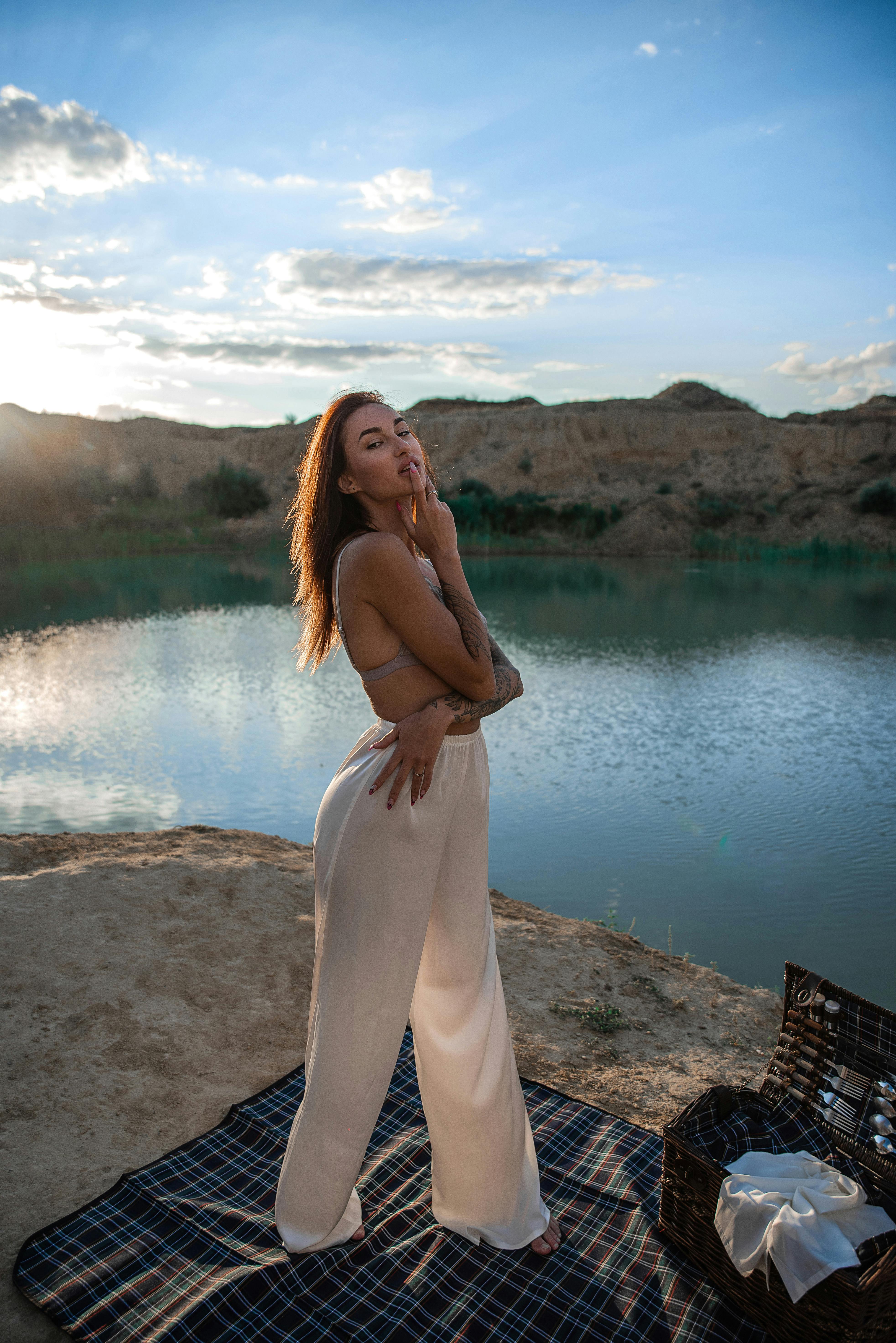 在宁静的户外场景中，日落时分，一位优雅的女子在湖边摆姿势