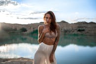 在日落时分，一名女子在湖边摆姿势，纹身增添了她的风采