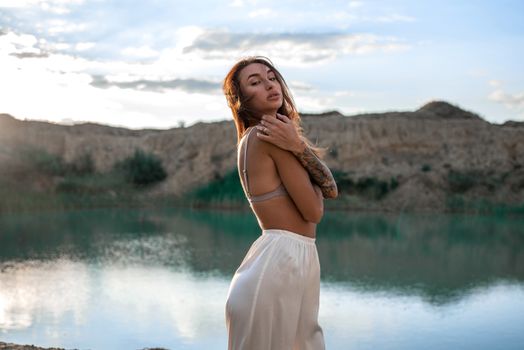 一个女人优雅地站在宁静的湖边，在日落时分散发着优雅和宁静