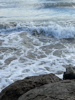 特写镜头捕捉到海浪冲击岩石，在海滩上产生泡沫