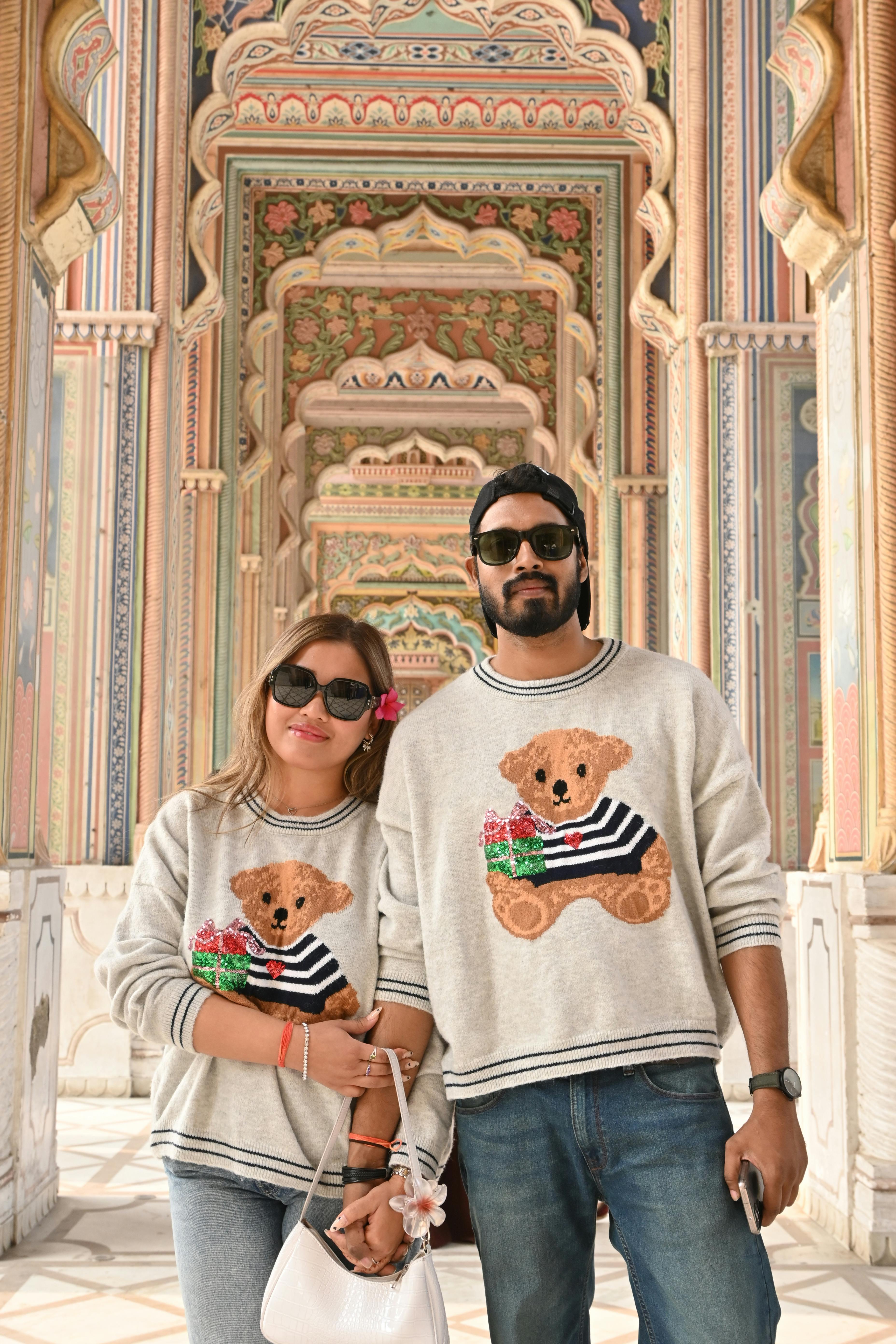 A stylish couple in matching sweaters posing at Jaipur's iconic Patrika Gate.