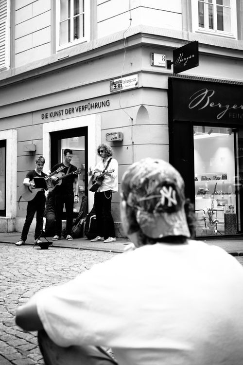 Free Black and white photo of street musicians playing guitars on a city corner while a passerby watches. Stock Photo