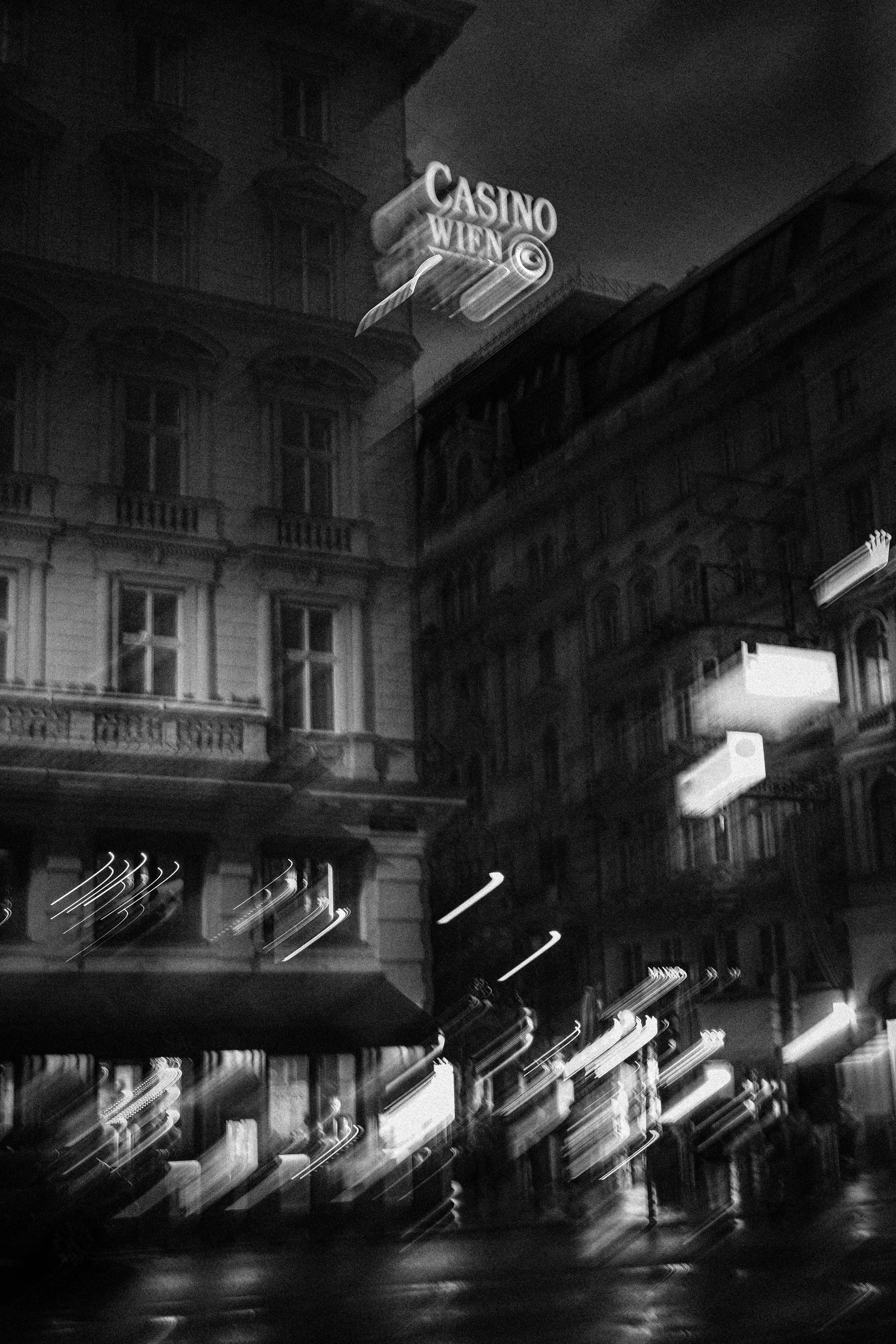 Artistic black and white view of Vienna's Casino Wien at night, highlighting motion blur effects.