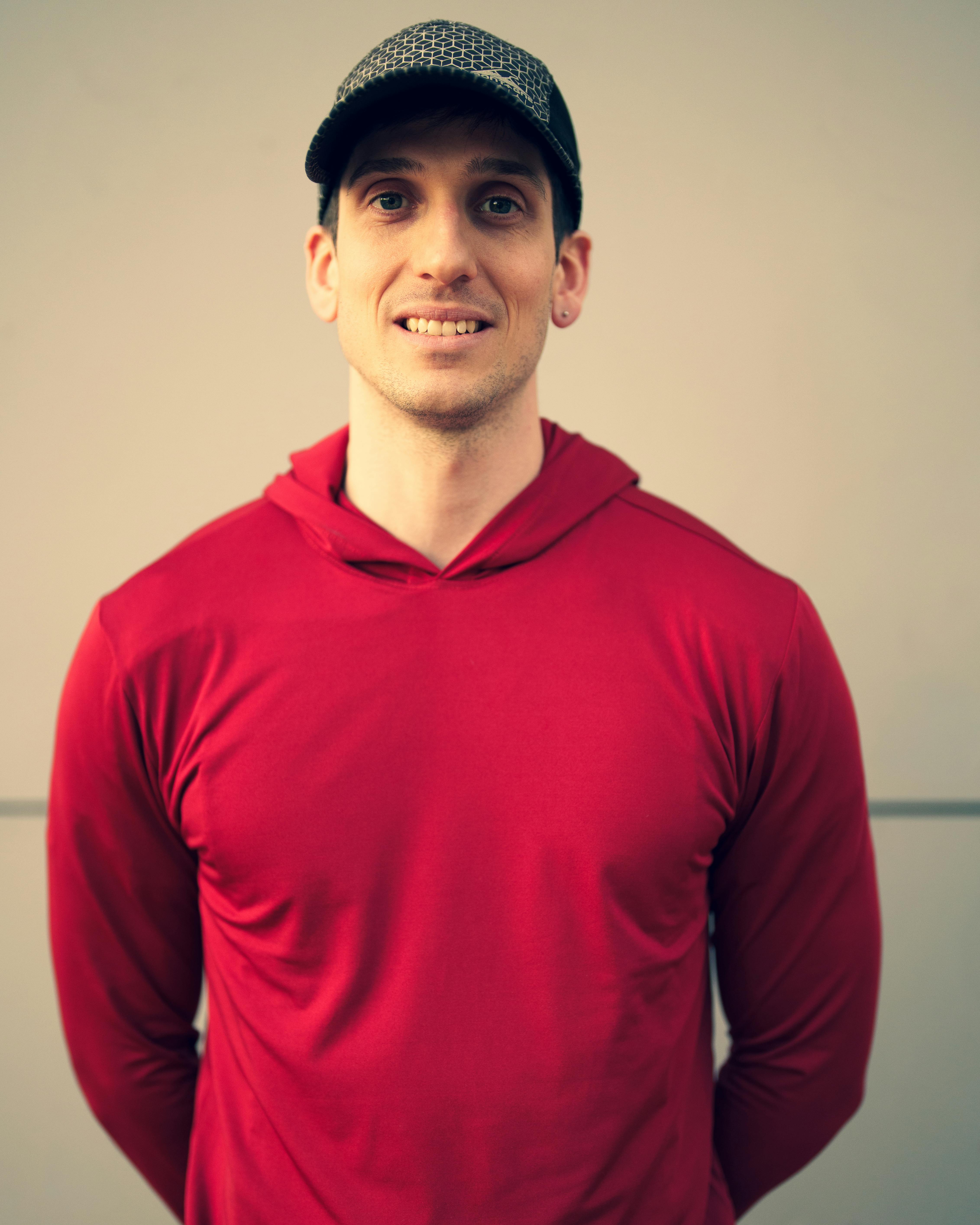 Portrait of a young man in a red hoodie smiling outdoors in Buenos Aires.