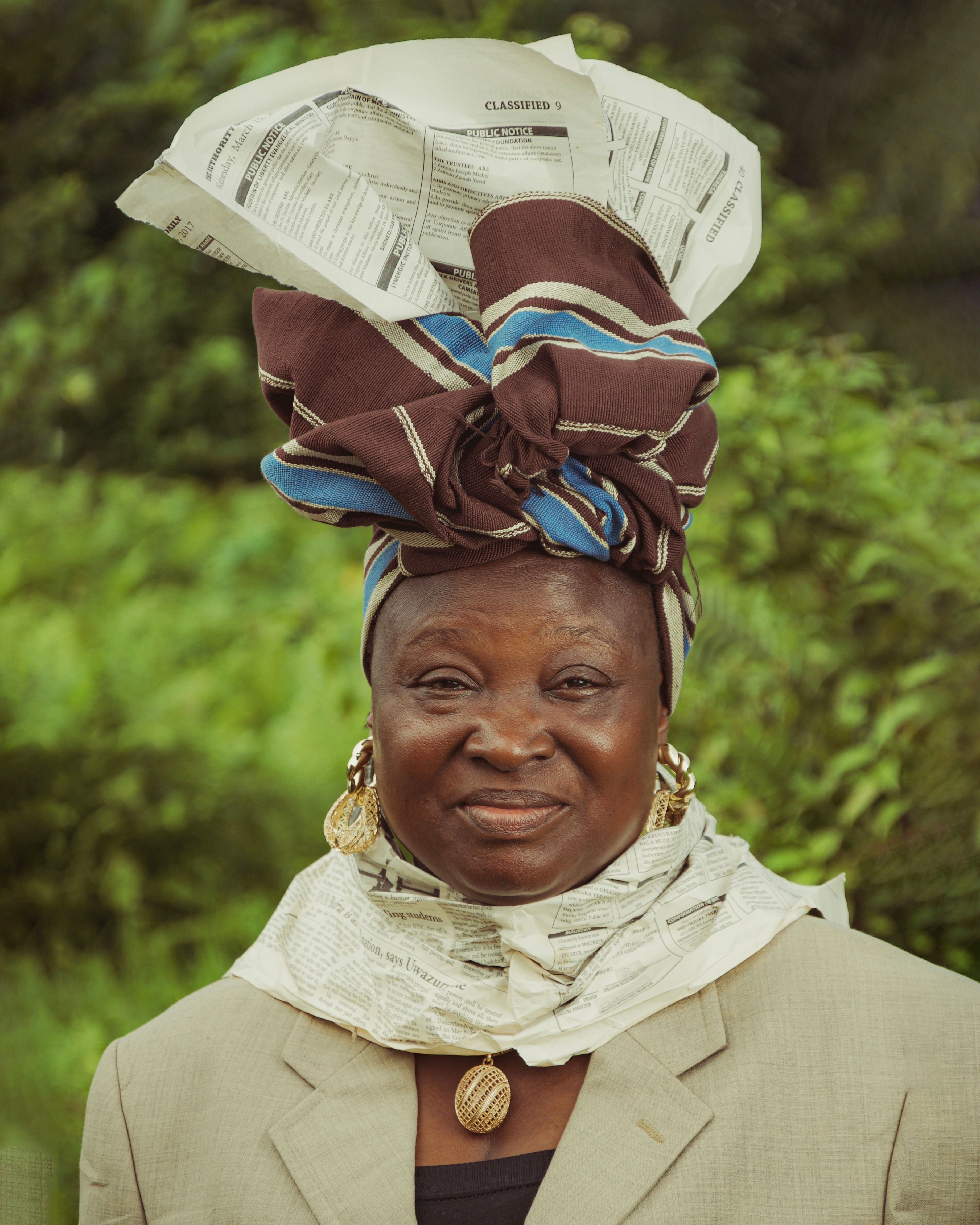 Portrait of a senior Nigerian woman wearing a unique headwrap, showcasing cultural fashion outdoors.