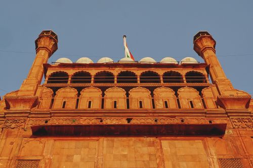 Free Upward view of the Red Fort with the Indian flag against a clear blue sky. Stock Photo