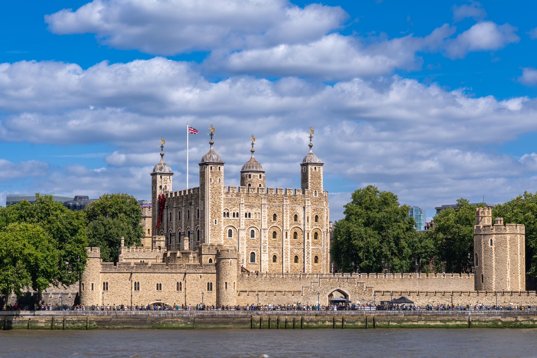 Historic Tower of London with blue sky and River Thames, a symbol of British royalty.
