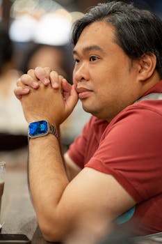 Portrait of a man in deep thought at a Vietnamese cafe, wearing a smartwatch.