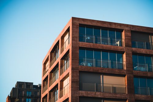 Free Contemporary city building facade with glass windows reflecting clear blue sky. Stock Photo