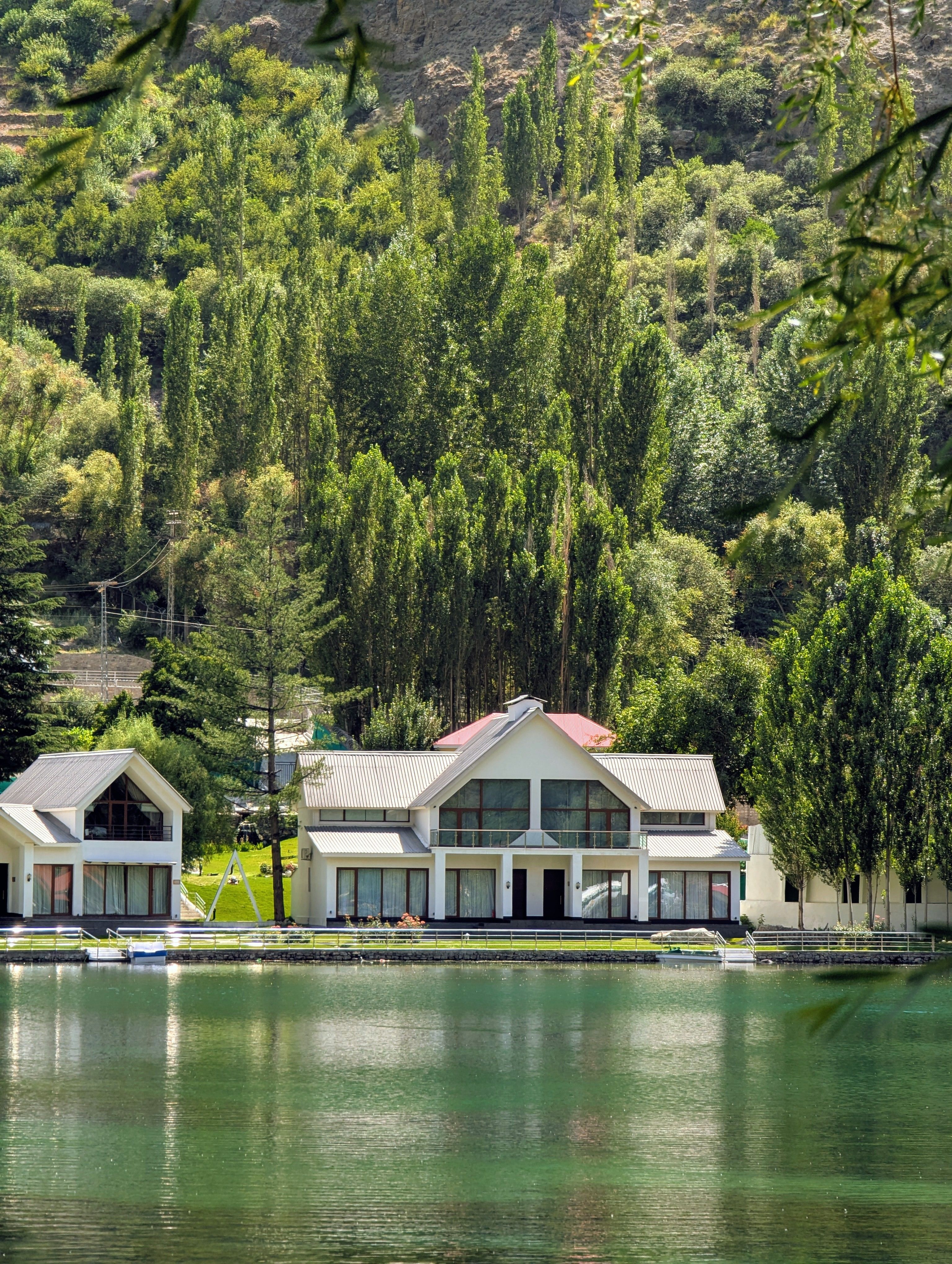 Lakefront house surrounded by lush forest and mountains, reflecting serenity and natural beauty