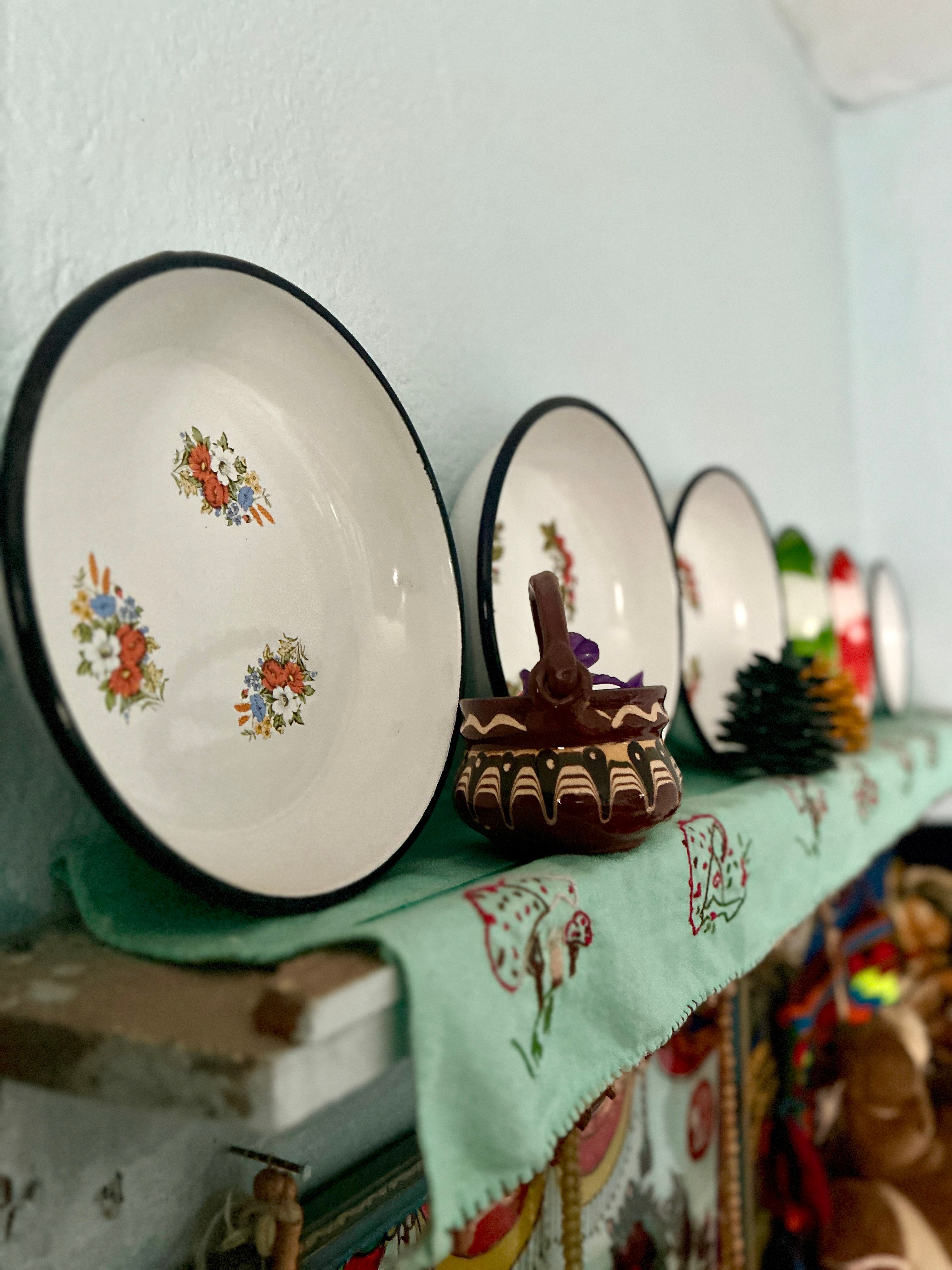Colorful decorative plates and ornaments on a rustic shelf with a vintage feel.