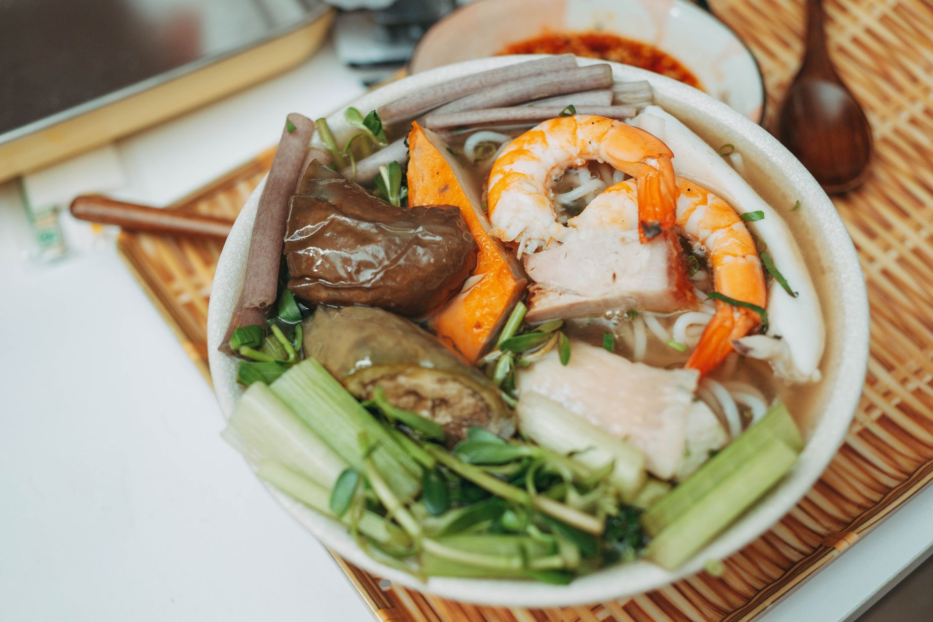 Appetizing bowl of Asian seafood noodle soup with shrimp and vegetables. Perfect for food lovers.