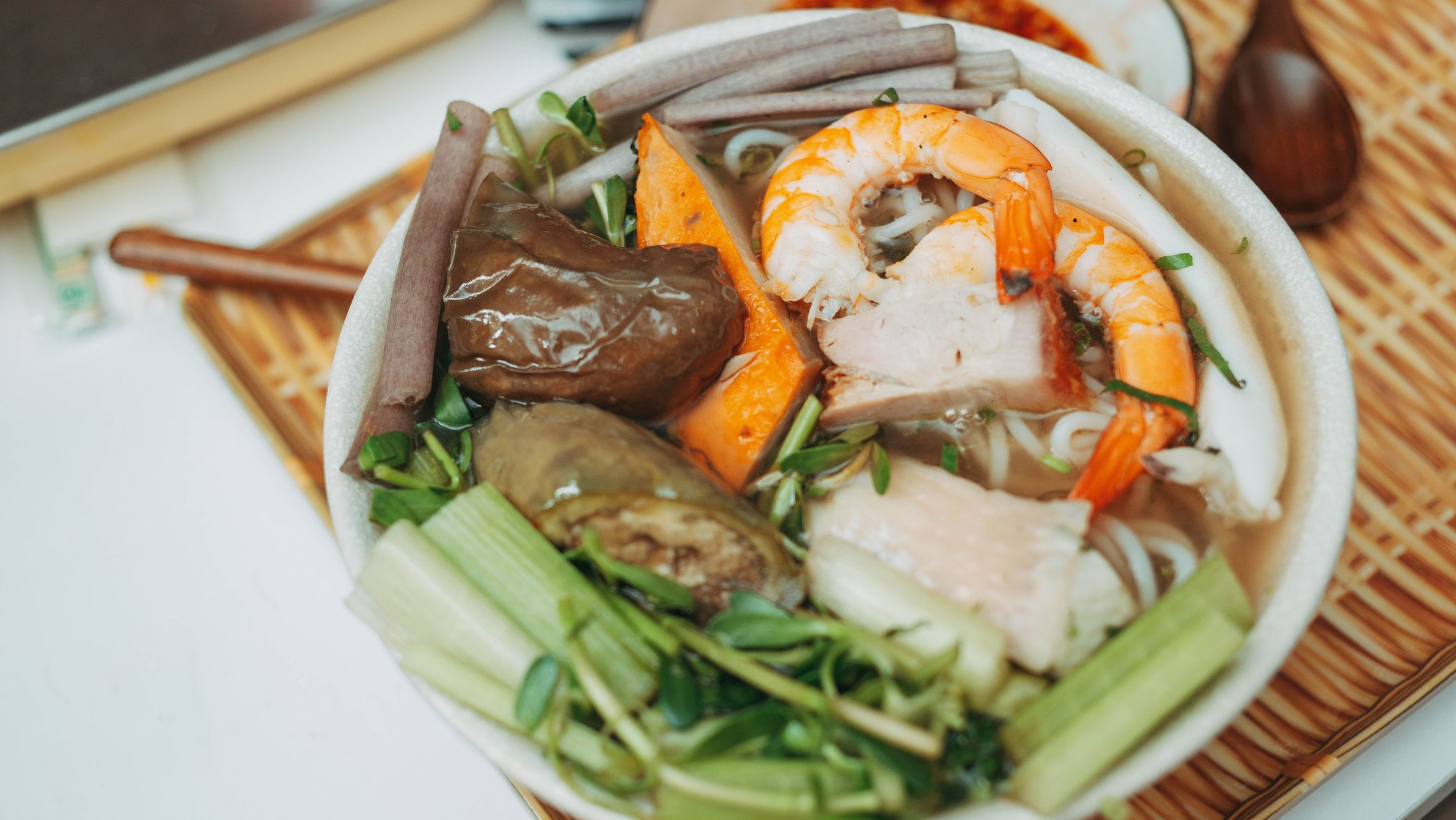 Appetizing bowl of Asian seafood noodle soup with shrimp and vegetables. Perfect for food lovers.