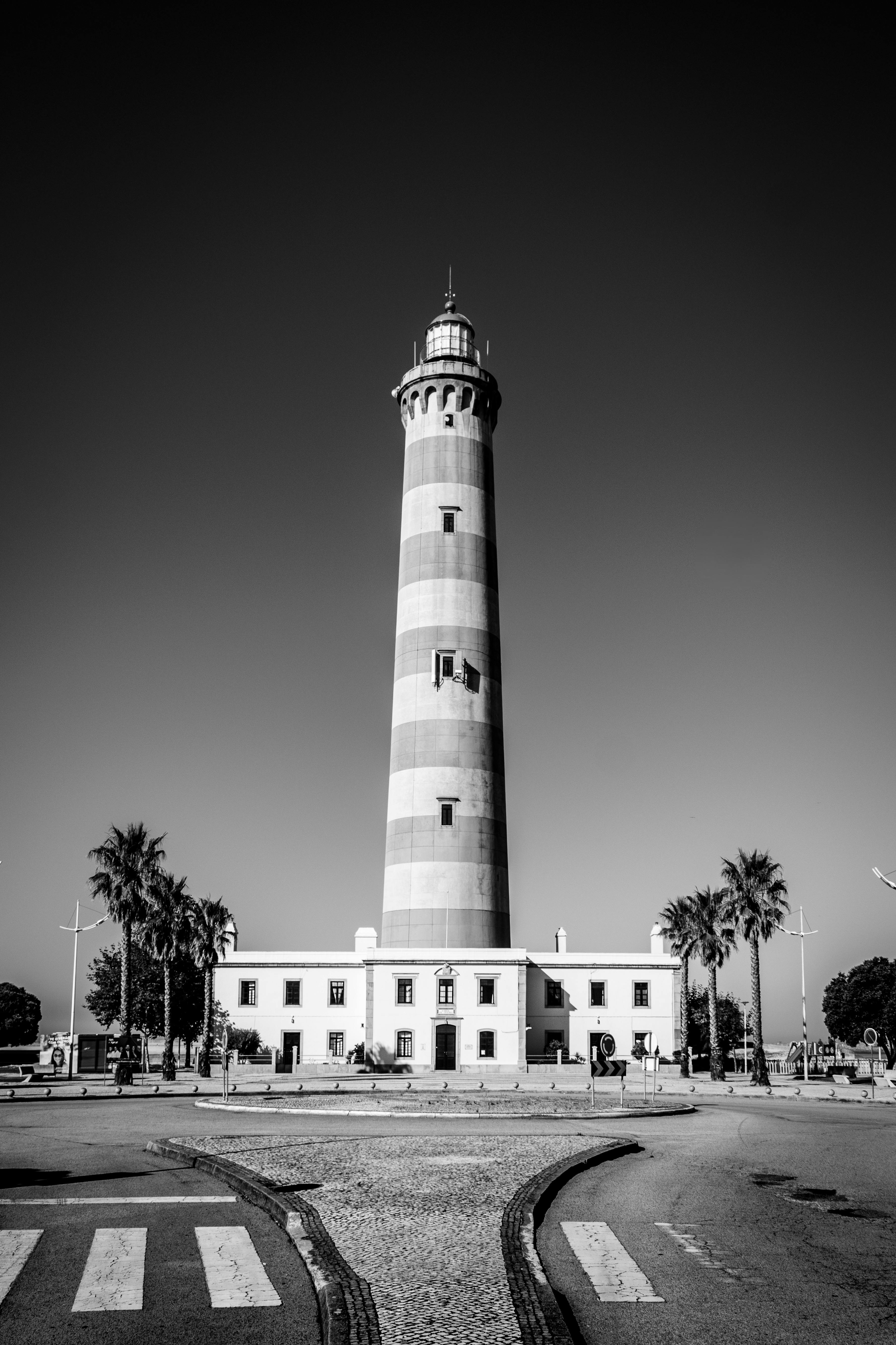 在晴朗的天空下，条纹灯塔的黑白图像显得格外清晰