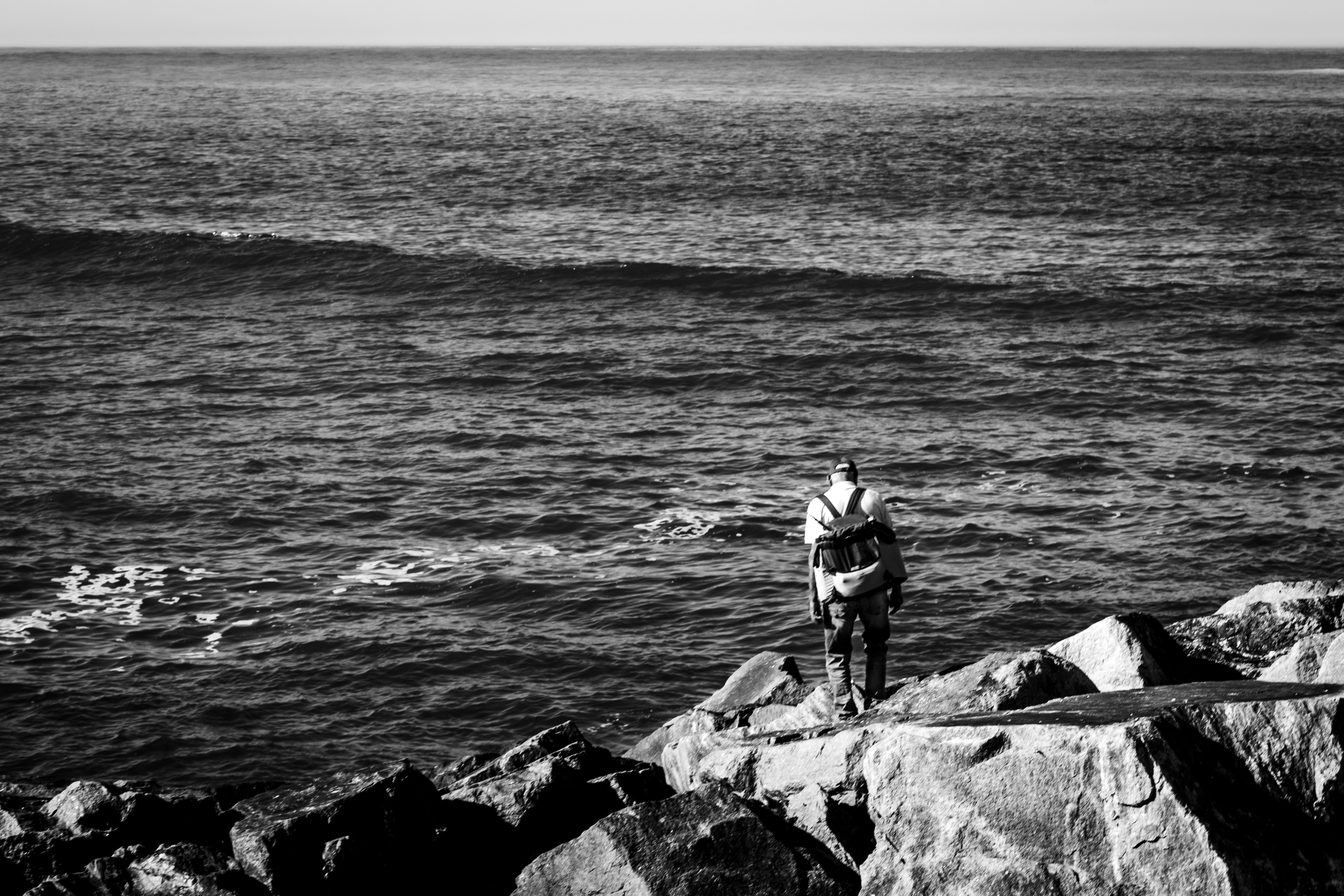 Solitary Figure on Rocky Shore by the Ocean · Free Stock Photo
