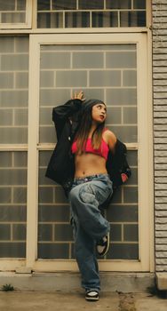 Young woman posing stylishly against urban backdrop in trendy outfit.