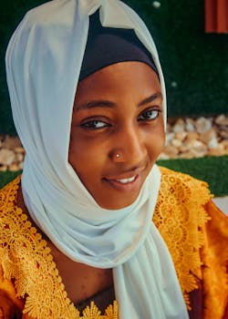 特写镜头捕捉到了一位女子，她戴着白色头巾，身穿着黄色蕾丝连衣裙