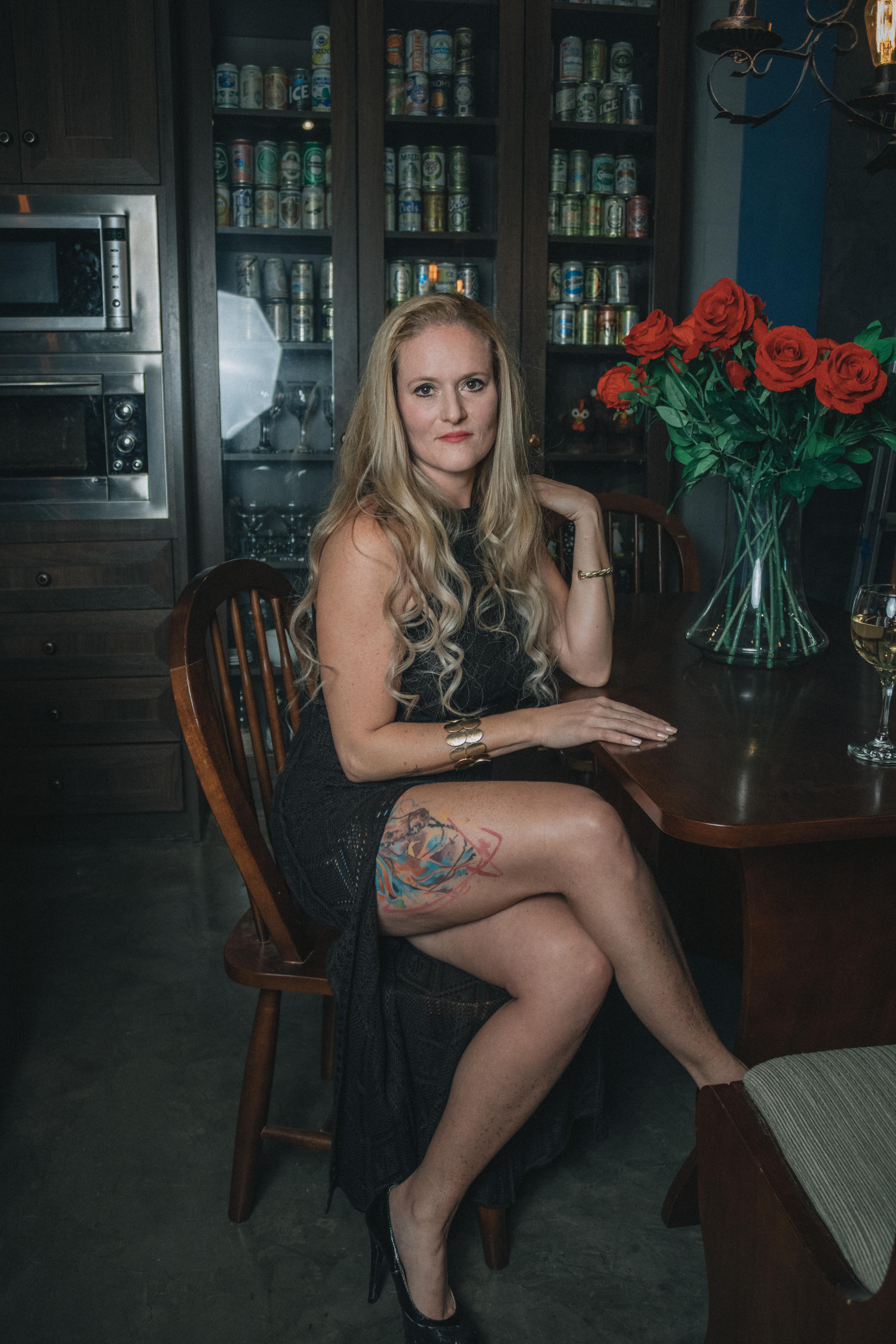 Безкоштовне Елегантна жінка сидить на кухні з квітковим татуюванням, оточена декором. стокове фото