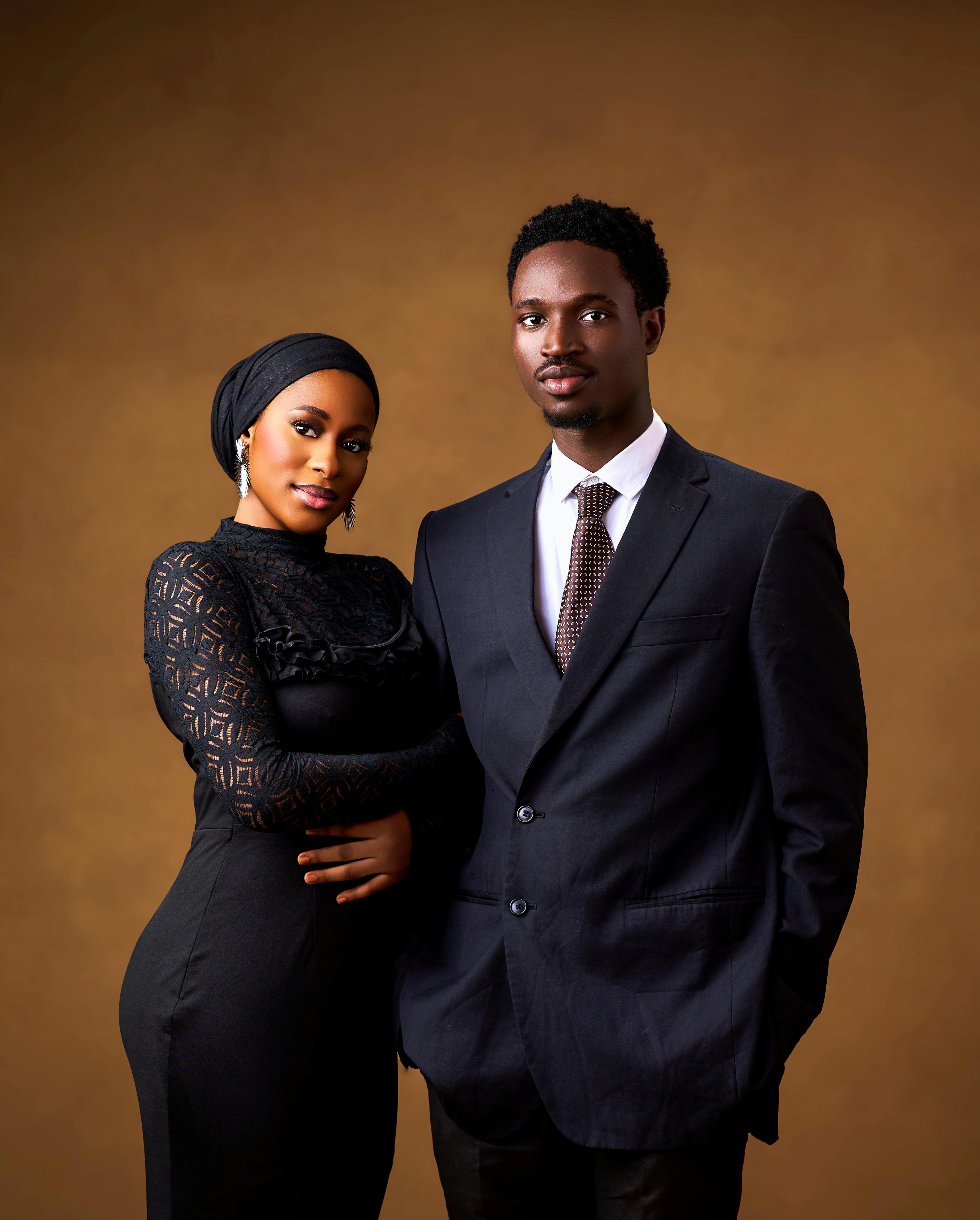 在温暖的背景前，时尚情侣穿着精致的正式服装