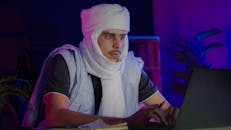 Focused Middle Eastern Man Working on Laptop at Night