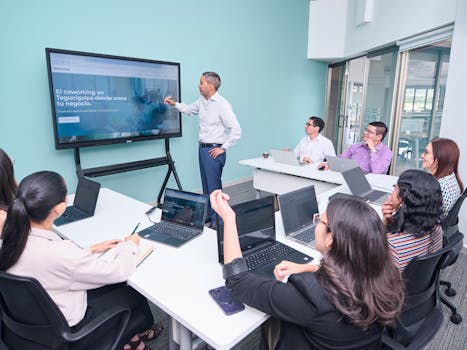 Professional team engaged in a business presentation with laptops and a projector screen.