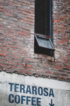 Rustic brick wall with open window above Terarosa Coffee sign.