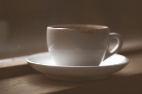 Free Close-up of a white espresso cup with saucer on a wooden windowsill, in soft light. Stock Photo