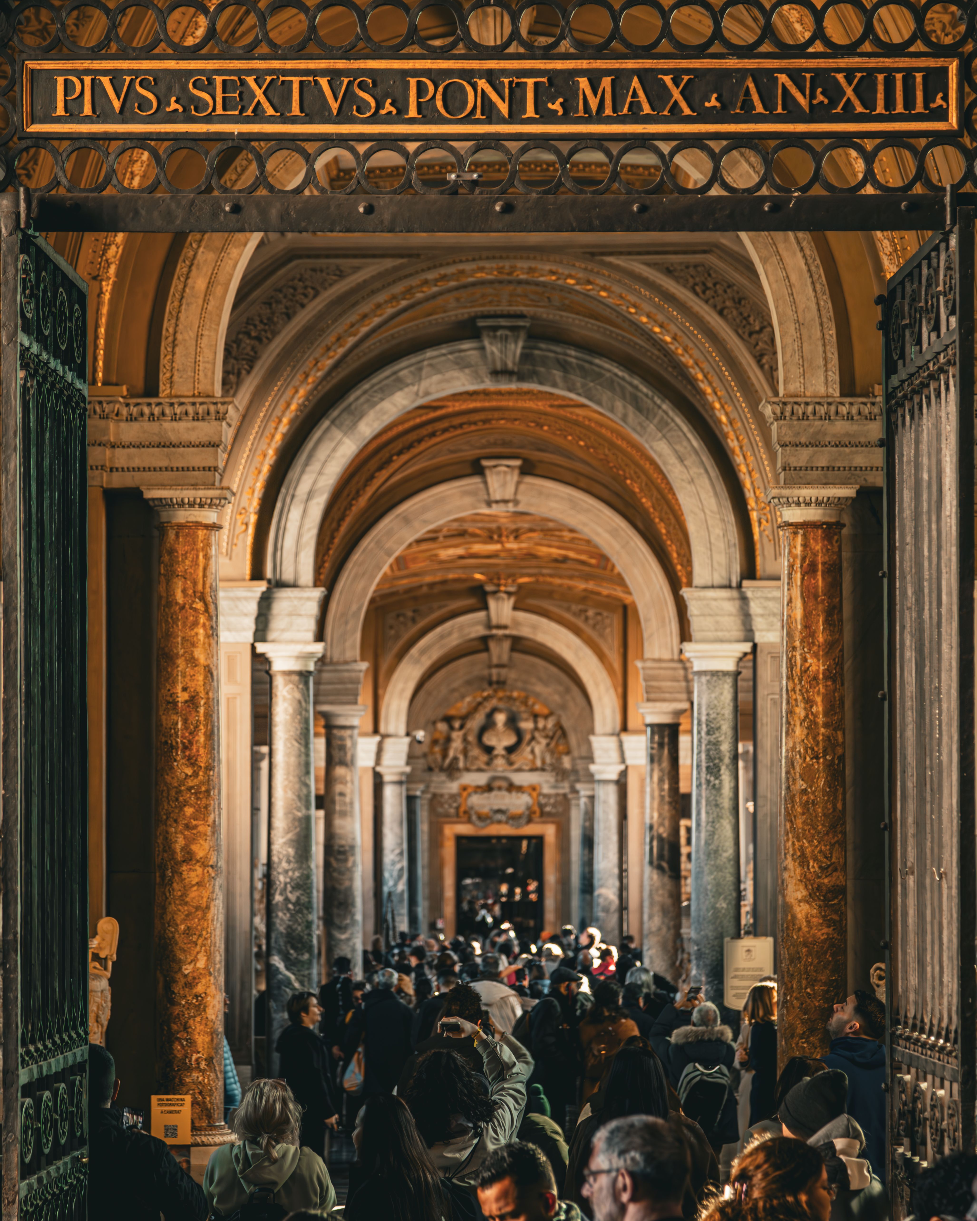 Busy corridor in Vatican Museum showcasing stunning arched architecture with a large crowd of visitors.