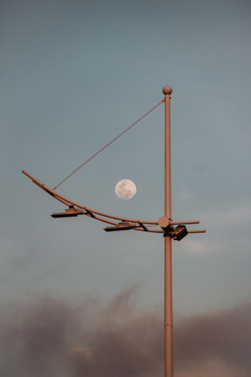 Free Street lamp silhouetted against a full moon in a serene evening sky. Stock Photo