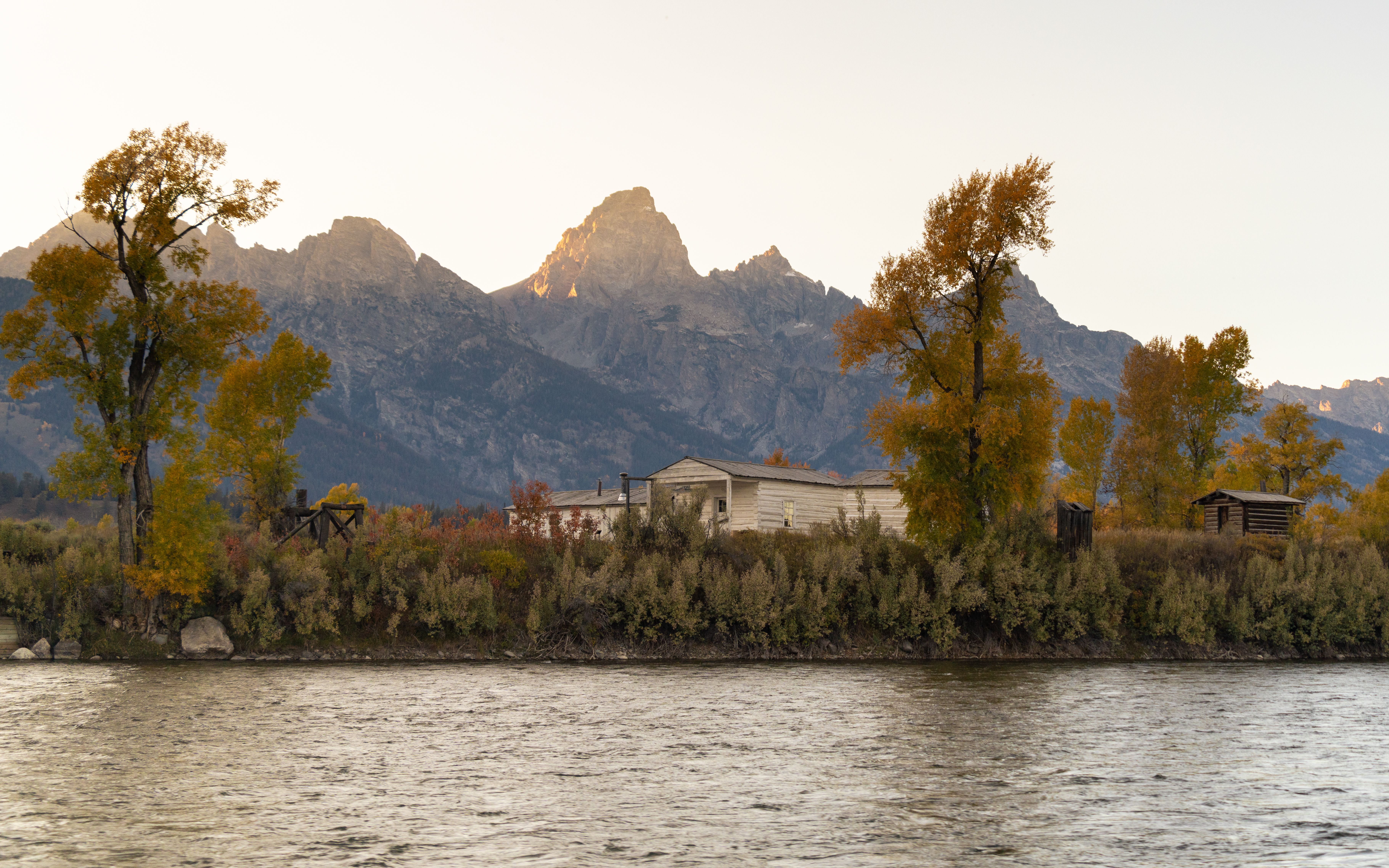 Stunning autumn scenery featuring mountains, trees, and a river in Grand Teton National Park, Wyoming.