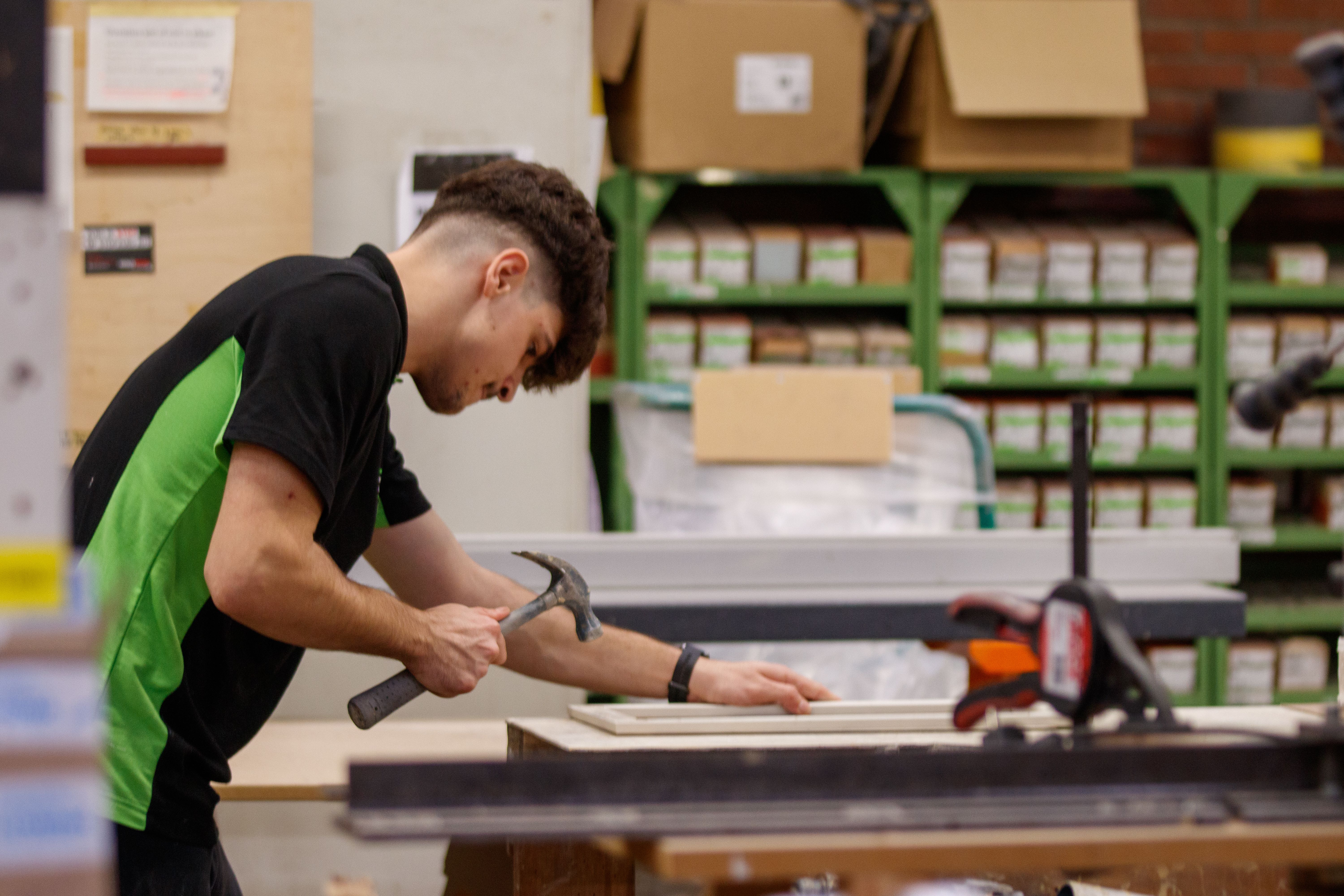 Young male carpenter focusing on woodworking project in workshop.