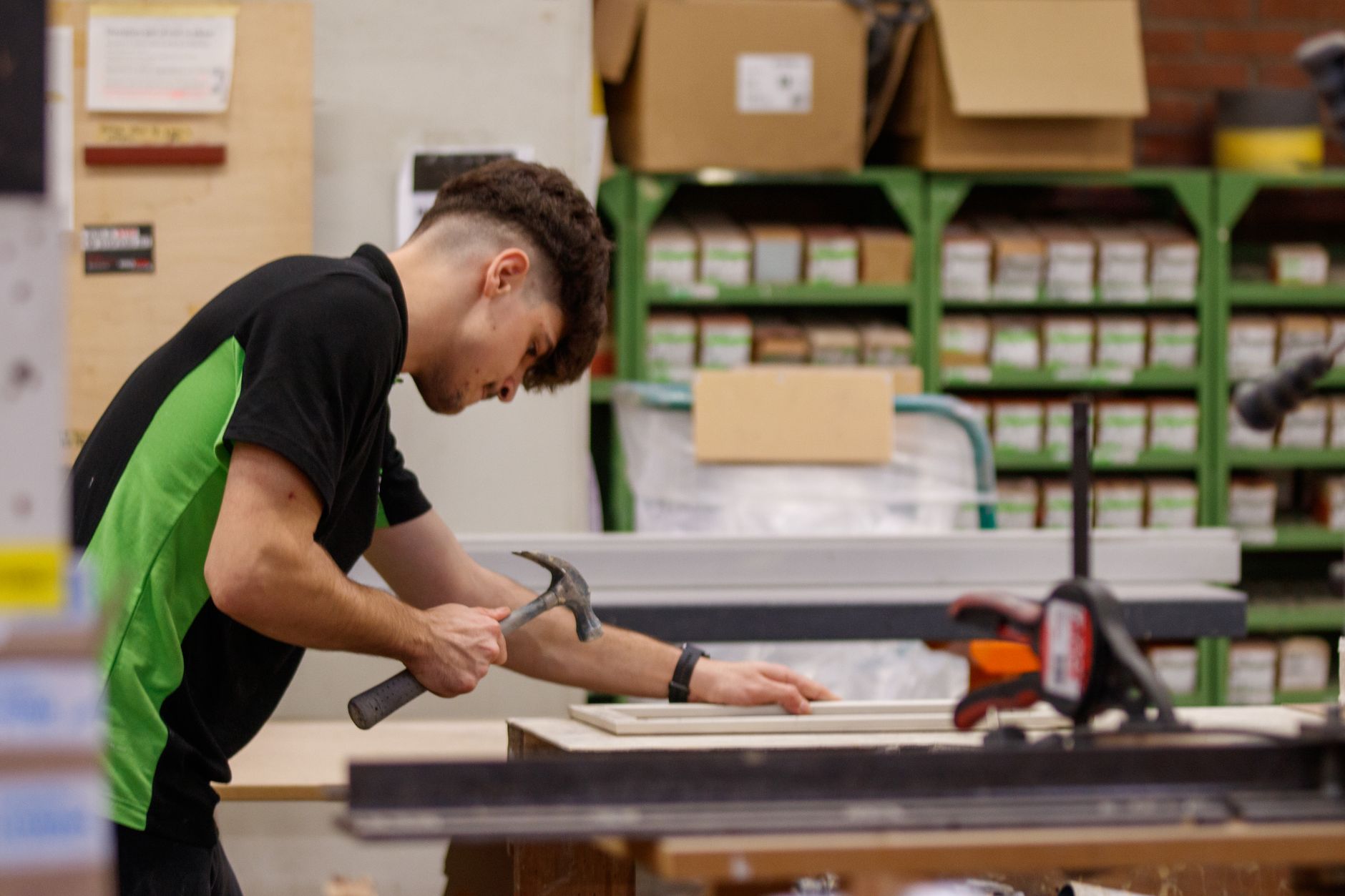 Young male carpenter focusing on woodworking project in workshop.
